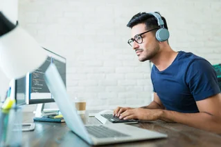 man on computer with headphones